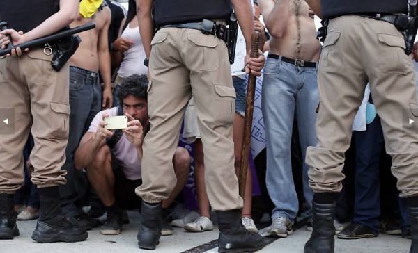 Manifestante "fura" bloqueio policial com celular durante protesto nos arredores do Mineirão, em Belo Horizonte. (Foto: Bernardo Salce)